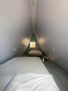 Cette petite chambre dispose d'un lit blanc et d'une fenêtre. dans l'établissement Chales Guarau, à Peruíbe