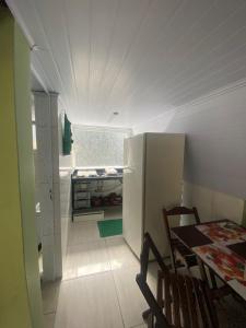 Il comprend une petite cuisine équipée d'une table et d'un réfrigérateur. dans l'établissement Chales Guarau, à Peruíbe