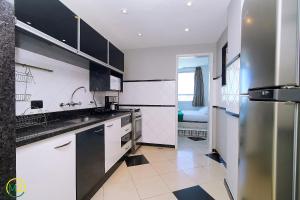 a kitchen with white cabinets and black and white appliances at Oceanfront penthouse with private pool Copacabana in Rio de Janeiro