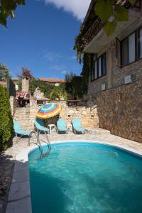 a swimming pool with a umbrella and chairs and a table at Casa de Artes Guest House in Balchik