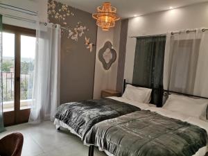 a bedroom with a bed and a chandelier and a window at Kostis Orange Resort in Volos
