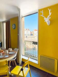 uma sala de jantar com uma mesa e uma grande janela em Le St Laurent - Ma Cabotte em Chalon-sur-Saône