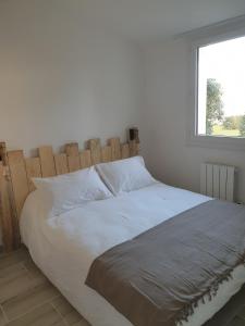 ドリュ・ドレロンにあるla belle cascadeの白いベッド(木製ヘッドボード付)が備わるベッドルームです。