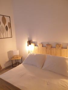 a bedroom with a white bed with a wooden headboard at la belle cascade in Dolus d'Oléron