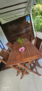 a wooden picnic table with two chairs and a plant on it at Les cottages de roseau in Capesterre-Belle-Eau