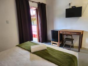 a bedroom with a bed with a desk and a chair at Pousada Delta Mar Maresias in Maresias