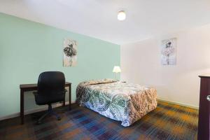 1 dormitorio con cama, escritorio y silla en Travelers Inn Beaver 