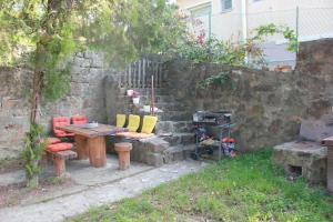 un patio con mesa, sillas y pared de piedra. en Alsópetényi erdőszéli vendégház, en Alsópetény
