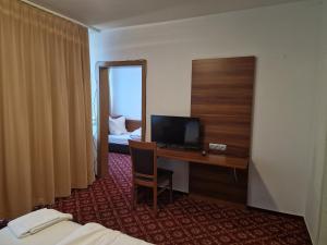 a hotel room with a desk with a television and a bed at Landhotel Neding in Hauenstein