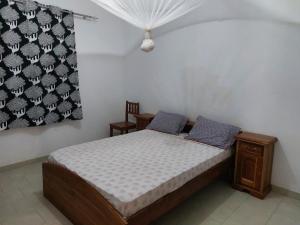 a small bedroom with a bed and a curtain at La maison Yaka in Boukot Ouolof