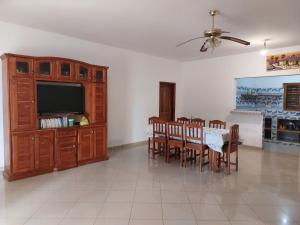 a dining room with a table and chairs and a television at La maison Yaka in Boukot Ouolof