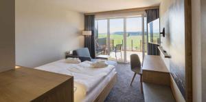 a hotel room with a bed and a balcony at Das Weitblick Allgäu in Marktoberdorf