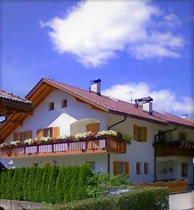 a building with a balcony with flowers on it at Landhaus Anita Dolomiten Kronplatz in Perca