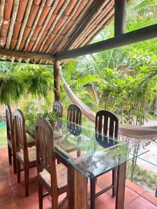 a glass table and chairs on a patio with a hammock at Chales do Oliveira in Porto Seguro