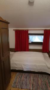une chambre avec un lit avec des rideaux rouges et une fenêtre dans l'établissement Ferienwohnung Zahnder inkl. Chiemgaukarte, à Ruhpolding