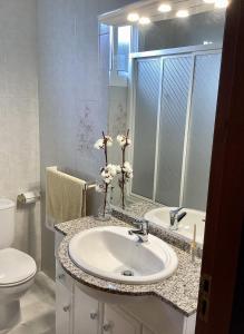 bagno con lavandino, servizi igienici e specchio di Apartamento de 3 Habitaciones y un baño SIN cocina en San Vicente de O Grove a San Vicente de O Grove