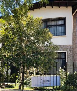 un árbol frente a un edificio con una valla en Oriente Hostal, en Talca