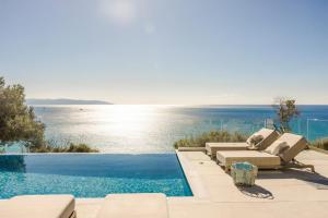 uma piscina com cadeiras e vista para o oceano em My Villa Kefalonia Lourdas Beach em Kefalonia