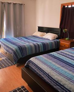 a bedroom with two beds and a table with a lamp at Hostal Al Yaras in Coquimbo