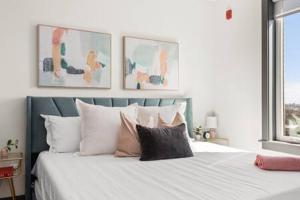 um quarto com uma cama com lençóis brancos e almofadas em Downtown Dolly - Stylish Airy and Cozy em Nashville