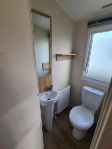 a small bathroom with a toilet and a sink at Happy Days Caravan Primrose Valley in Filey +19 photos