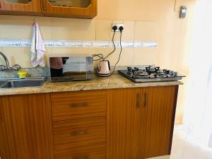 a kitchen counter with a stove and a sink at Casa Mia BnB in Kampala