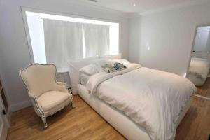 a white bedroom with a bed and a chair at Modern 3BR 2BA Home w Patio Outdoor Salt Pool in East Hampton