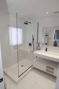 uma casa de banho branca com um chuveiro e um lavatório. em Modern 3BR 2BA Home w Patio Outdoor Salt Pool em East Hampton
