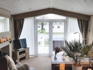 a living room with a large window and a television at Forest Getaway, sleeps 6 at Bashley, leisure PASS included in New Milton