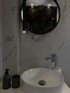 een badkamer met een witte wastafel en een spiegel bij Tirana Elegant Apartment in Tirana