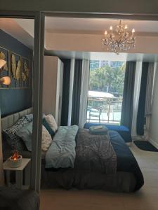 Un dormitorio con una cama y una ventana con una lámpara de araña. en Cozy Staycation - Azure Urban Resort Residences, en Manila