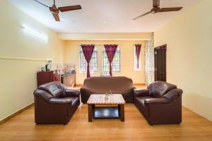 Le Mission Stay في بونديتْشيري: كرسيين جلديين وطاولة في غرفة المعيشة