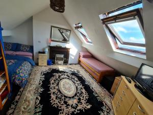 a attic room with a bed and a tv and windows at Large private room in Biddulph-Stoke On Trent in Biddulph
