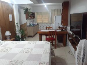 ein Schlafzimmer mit einem Bett und einem Tisch sowie eine Küche in der Unterkunft Loft conceito aberto - 4 pessoas in Araranguá