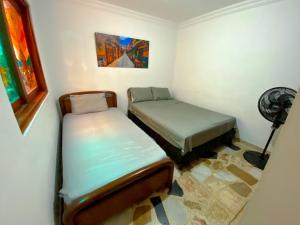 two beds in a small room with a fan at Casa EstadioMed in Medellín