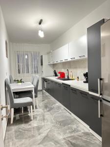 una cucina con armadi bianchi, tavolo e sedie di Coresi Mall Area Studios & Apartments by GLAM a Braşov