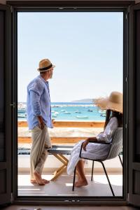 a man and woman standing in a window looking at the beach at KIANO SUITES in Kampos Paros