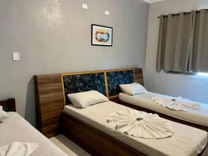 a room with two beds and a clock on the wall at Hotel Anchieta São Bernardo do campo in São Bernardo do Campo