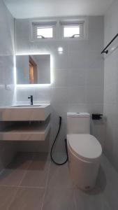 a white bathroom with a toilet and a sink at PKK hotel Residence in Bang Phli