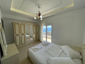 a white bedroom with a large bed and a window at Villa Sildi in Sarandë