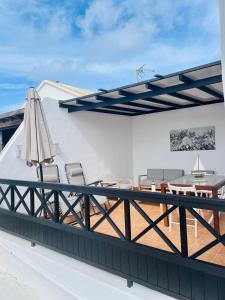 una terraza en la azotea con sillas y sombrilla en Apartamento con amplia terraza en la playa, en Puerto del Carmen