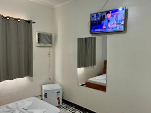a room with a tv on a wall with a mirror at Hotel Sunshine in São Bernardo do Campo