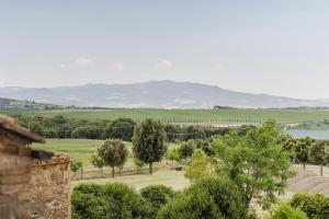 Blick auf ein Feld mit Bäumen und einen See in der Unterkunft Antica Grancia Di Quercecchio in Montalcino
