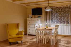 een eetkamer met een tafel en een gele stoel bij Turciansky dvor - Apartmany Turiec in Martin
