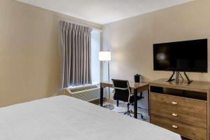 a hotel room with a bed and a desk and a television at Suburban Studios in Raleigh