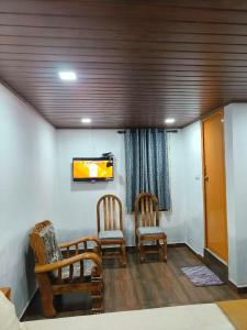 uma sala de estar com duas cadeiras e uma televisão em Coorg view estate Homestay em Madikeri