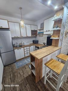 a kitchen with white cabinets and a wooden counter top at Apartman Una in Zrenjanin