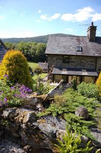 a garden in front of a stone house at Tre-Allt Gorgeous Cottage in Dolgellau