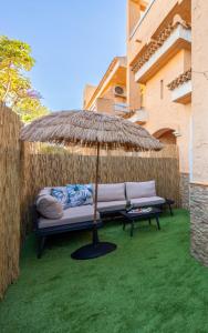 a couch sitting under an umbrella on a lawn at Chill-out # Piscina todo el año # Playa a 650m in Vera