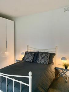 a bedroom with a bed with a black blanket and pillows at DIDSBURY Fáilte Inn Apts - 3 Mins to The Christie's - Ground Floor - FREE Parking in Manchester